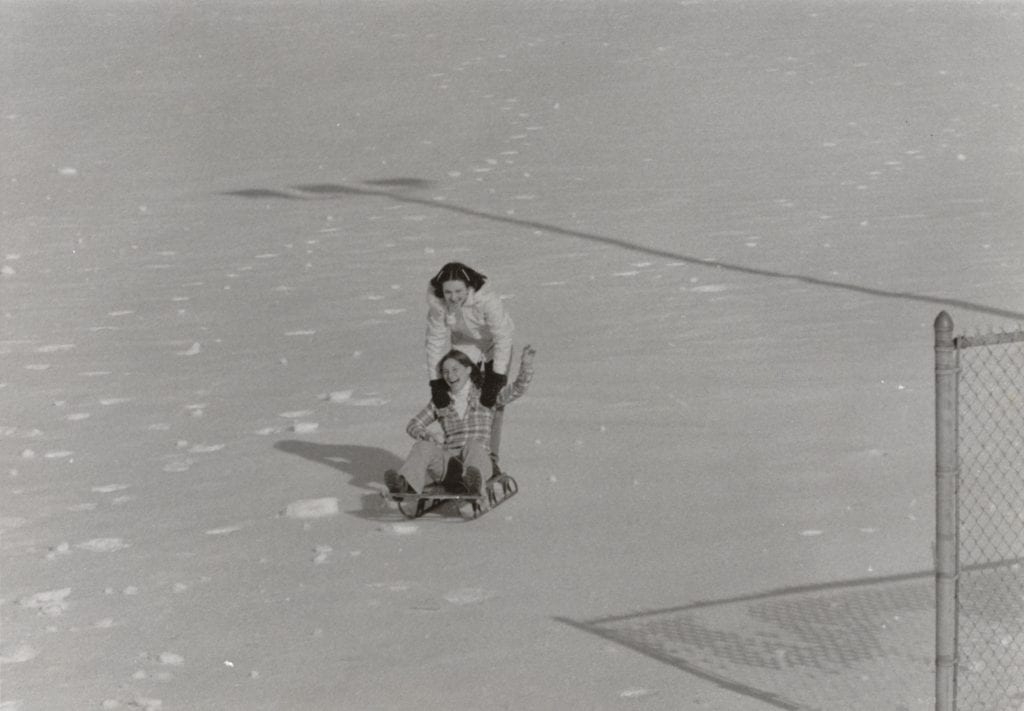 Image of two young women sledding during the blizzard of 1978